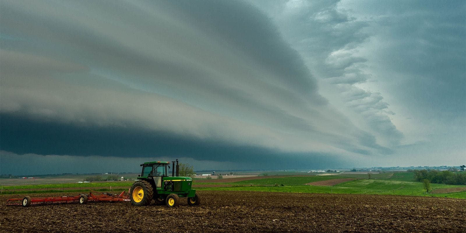 A tractor pulls a disc through a field on a cloudy day at the Tranel farm in Wisconsin.