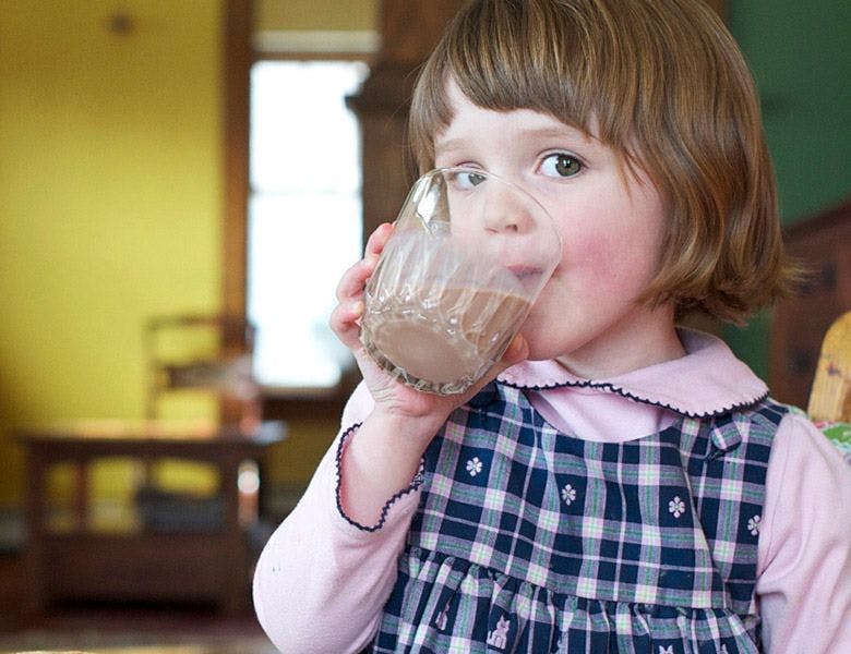 Little girl drinking milk out of glass.