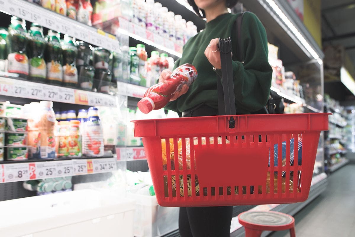 A women places dairy product in her shopping basket.