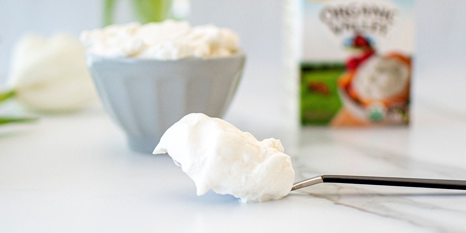Spoonful of whipped cream showing soft peaks.