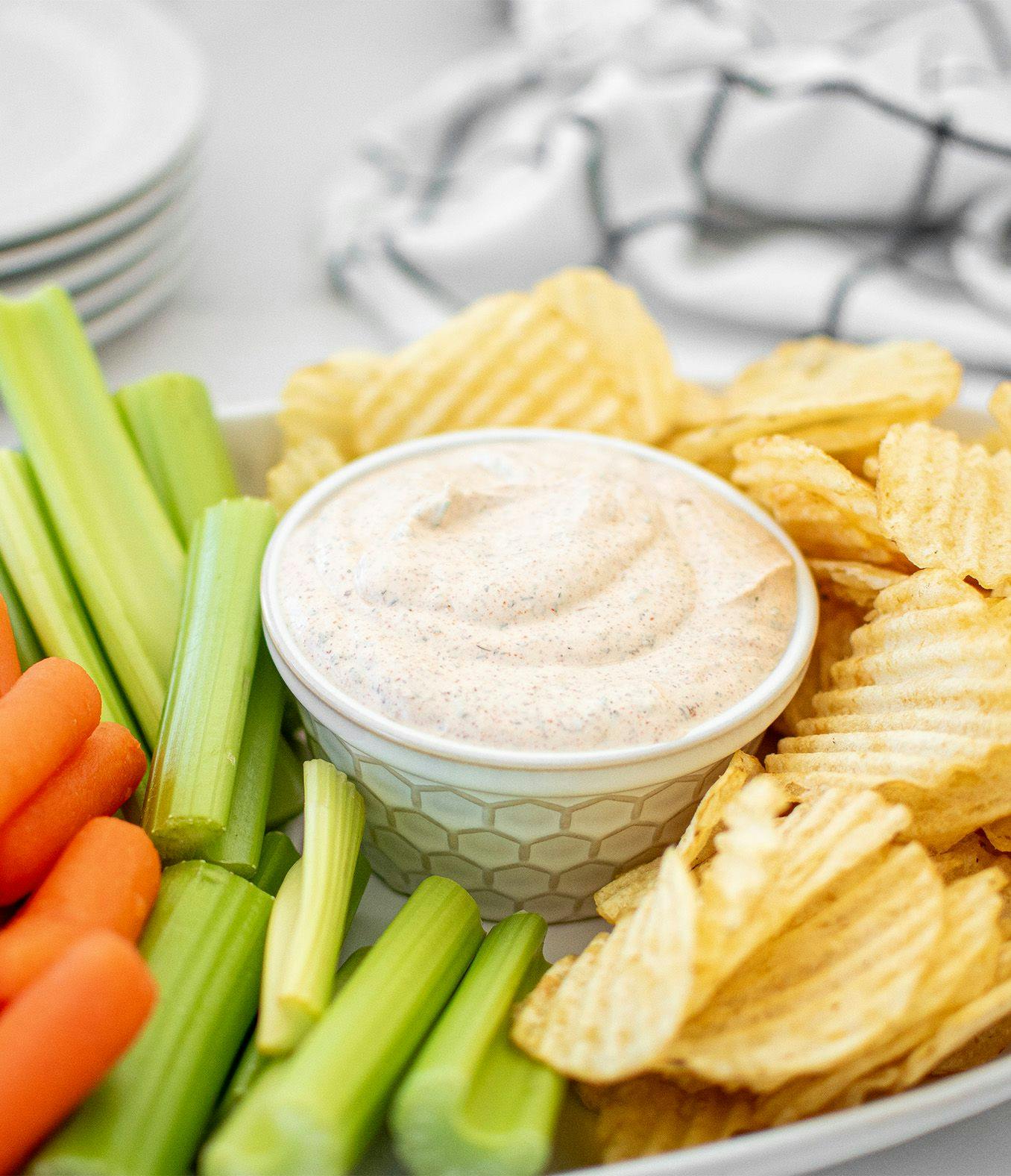 Organic Buffalo Ranch Dip with chips, celery and carrots on a serving dish.