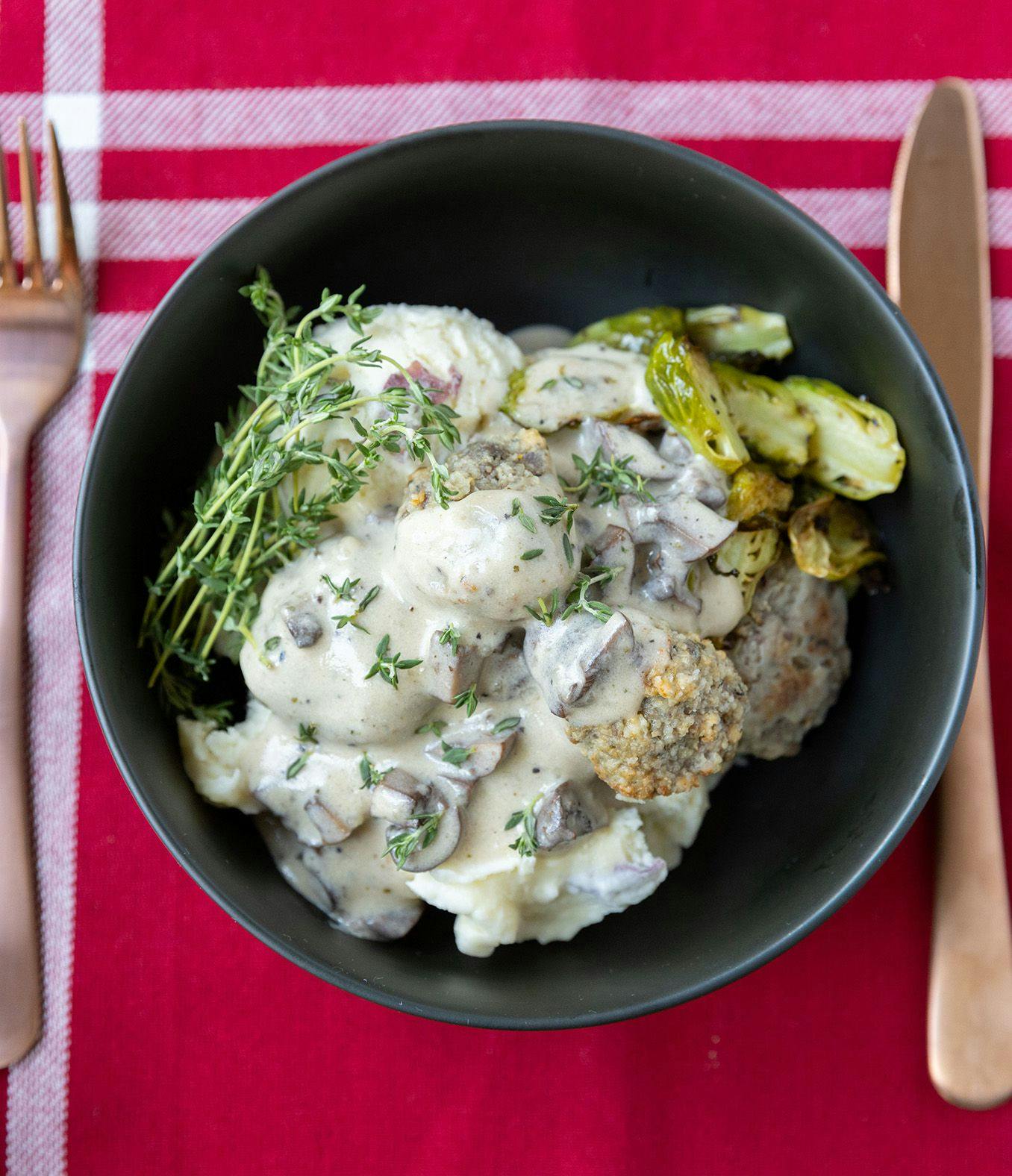 A bowl of potatoes and Swedish meatballs on a table