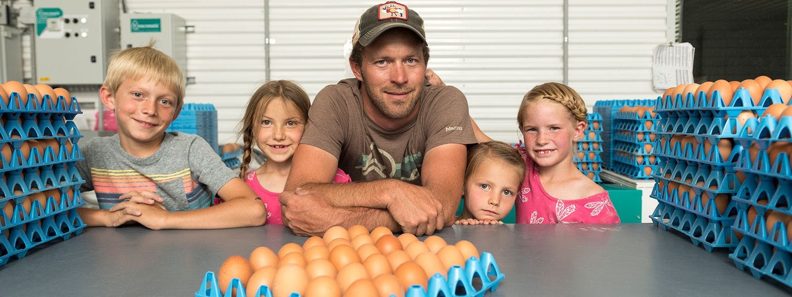 Farmer and his children surrounded by organic eggs.