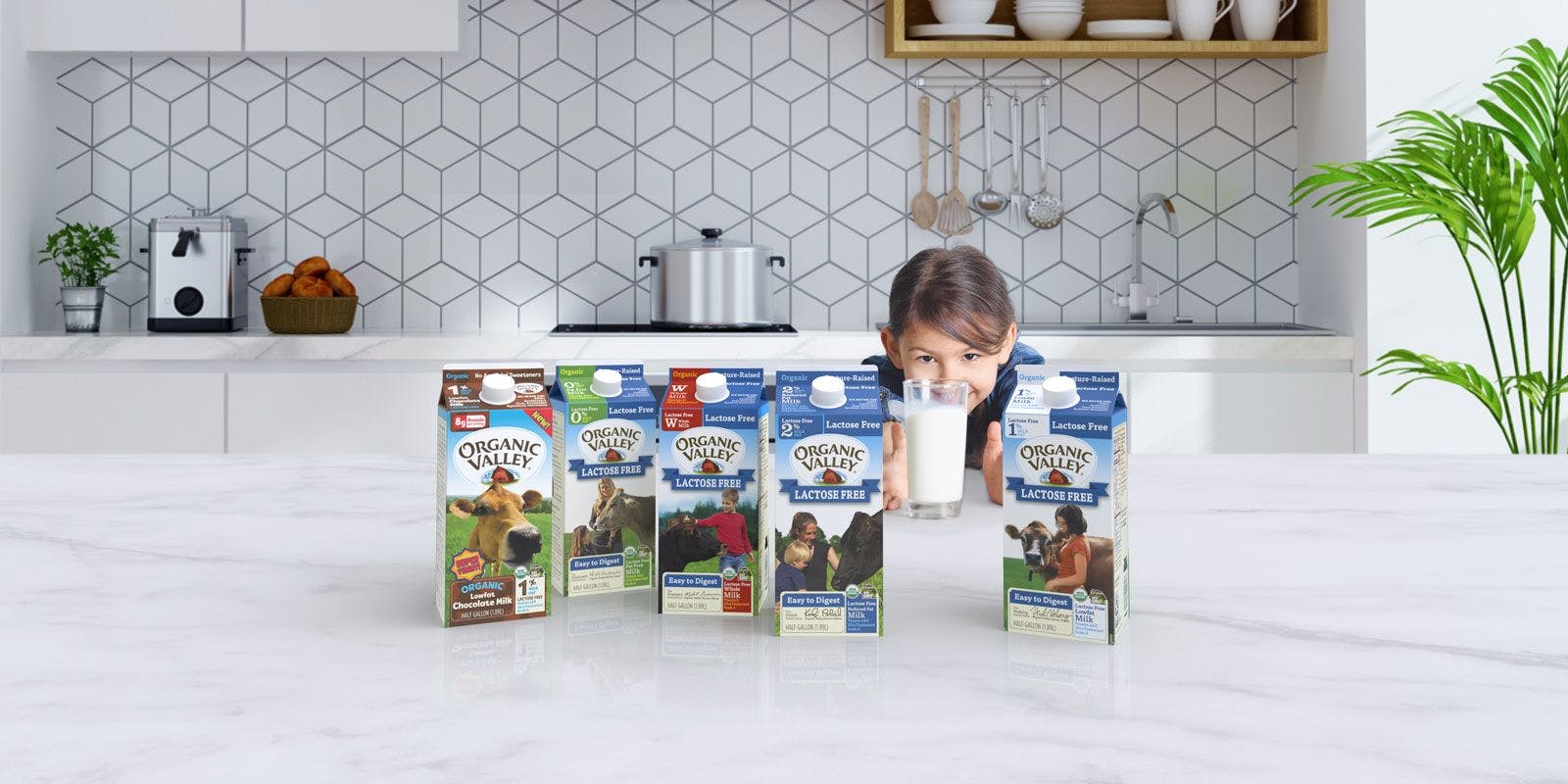 Young girl holds a glass of Organic Valley lactose-free milk and shows all the options for lactose-free milk.