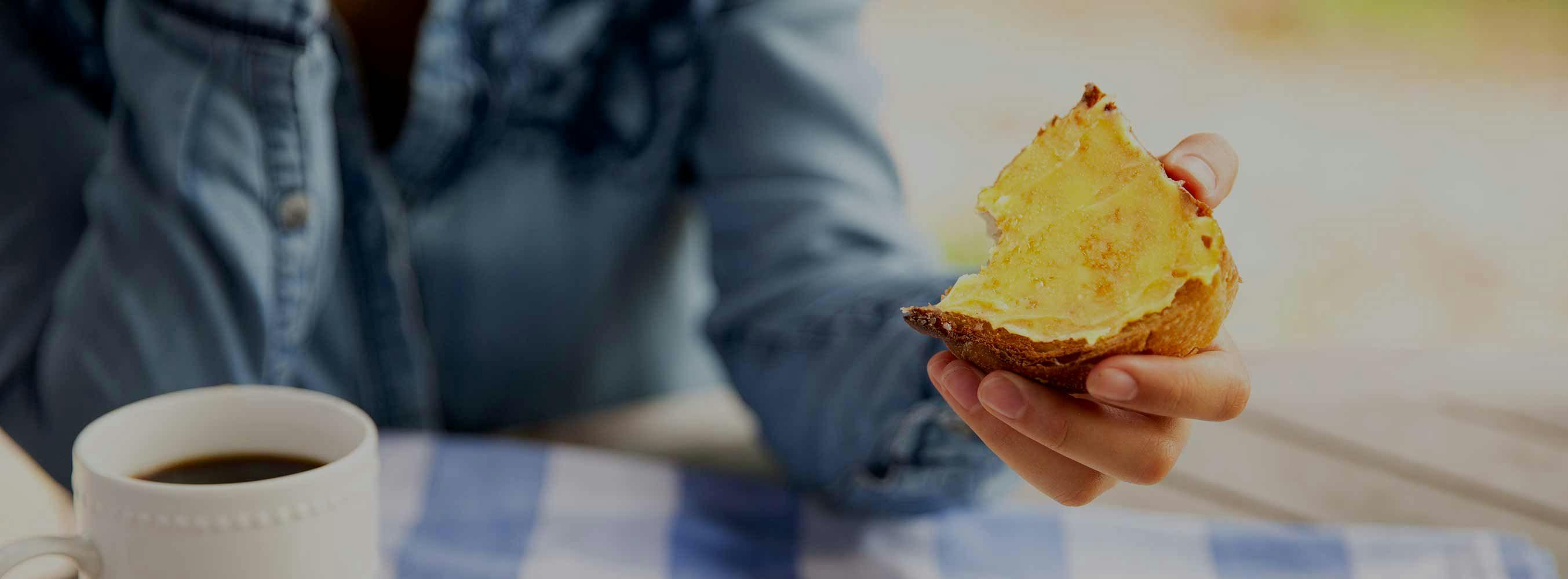 A person holding bread with ghee spread on top of it.