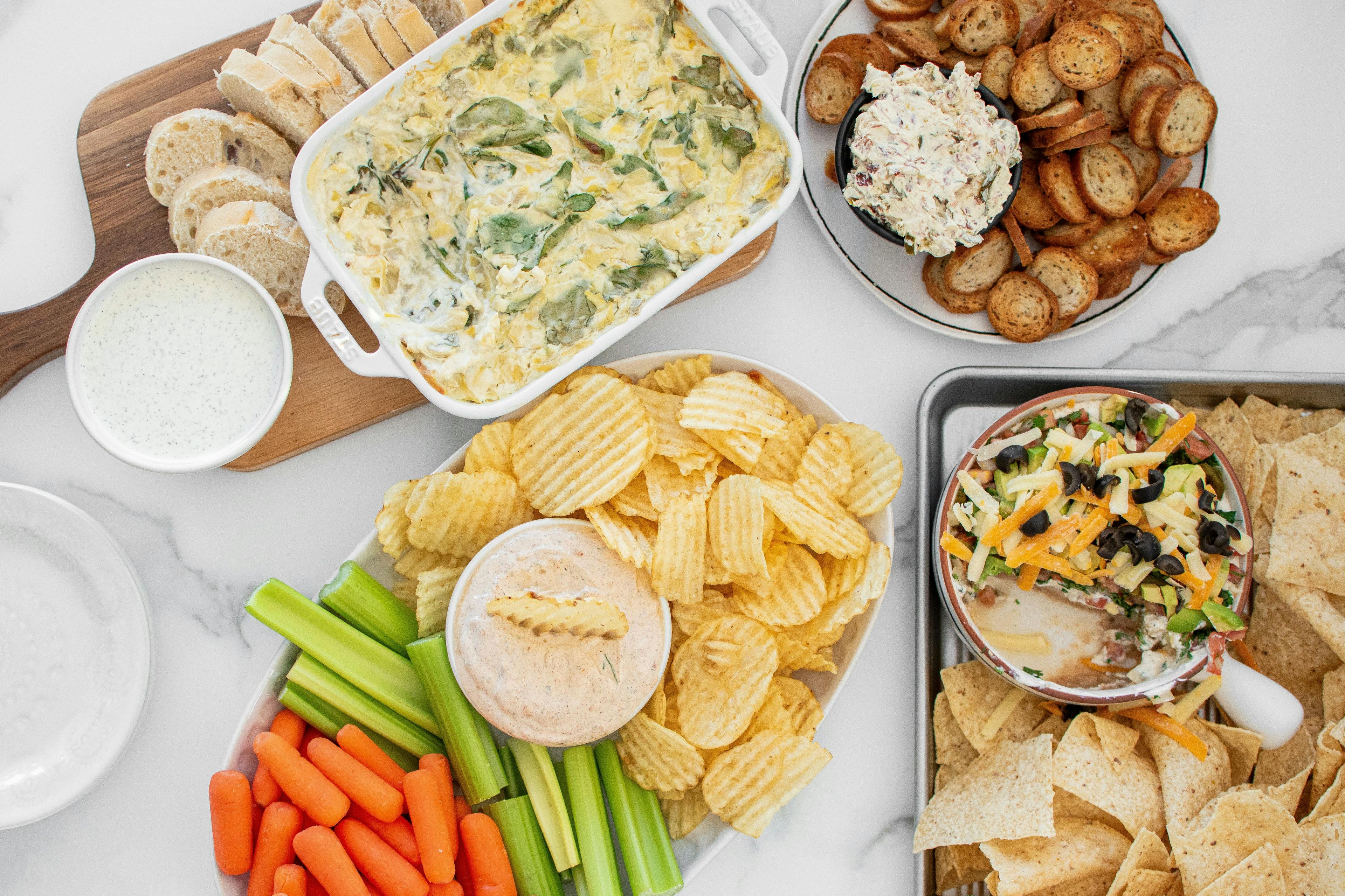 Game day dips displayed with chips, veggies and bread.
