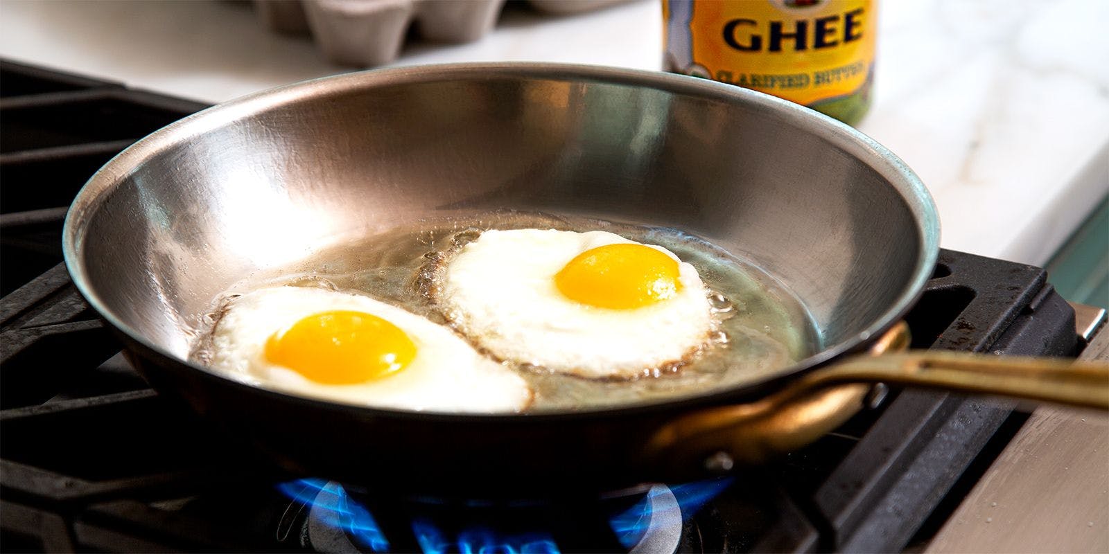 Two eggs fry in a pan over the stove with Organic Valley Ghee.