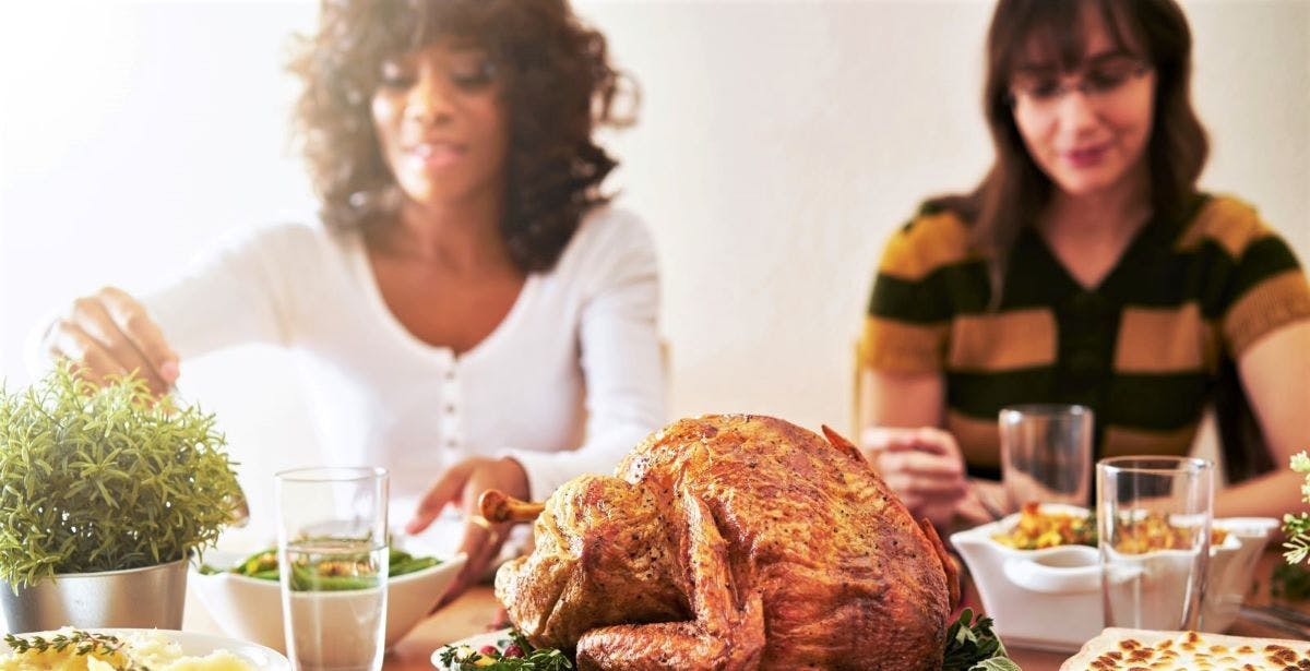 Two women eat turkey.