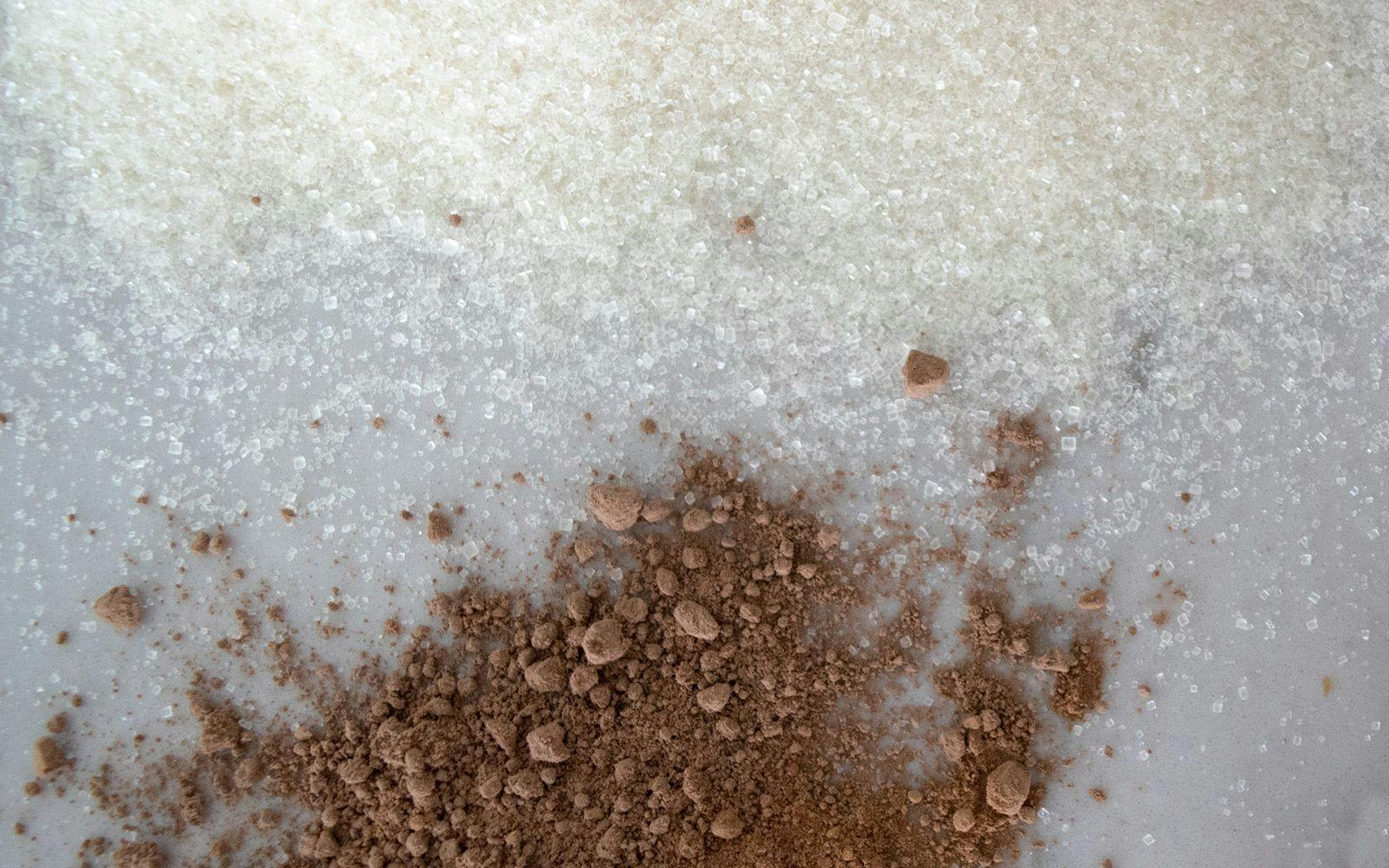 Fair trade cane sugar and cocoa powder sprinkled on a countertop.
