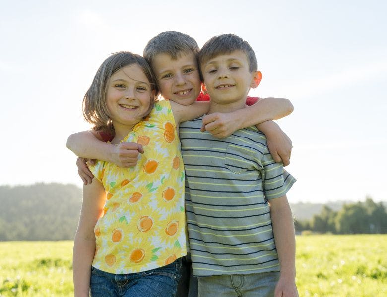 Three children hugging and smiling.