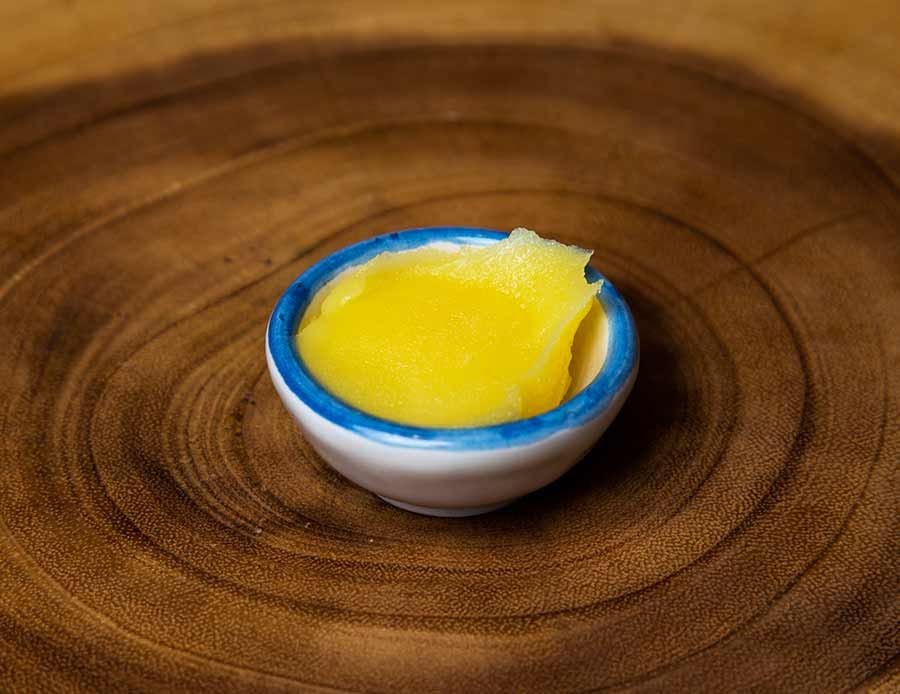 A bowl of ghee on a wooden board.