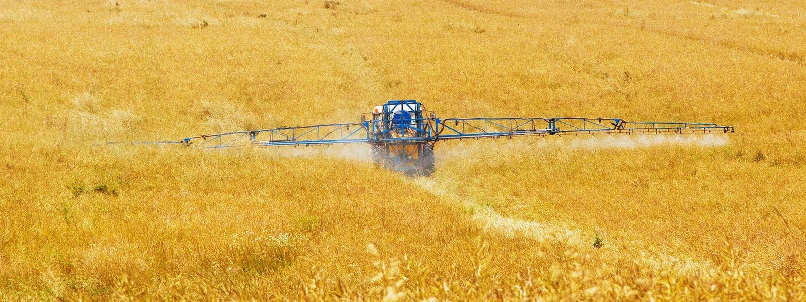 A tractor spraying crops with pesticides
