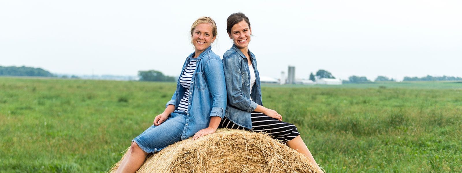 Sisters posing on a hay bale.
